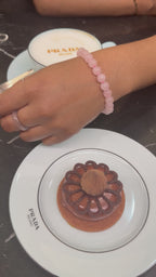 Rose quartz beaded bracelet worn on wrist, soft pink natural stone jewellery in lifestyle setting